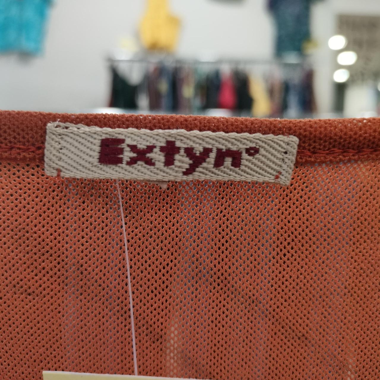 Close-up of a 'Extyn' label on a textured brown surface with a blurred background