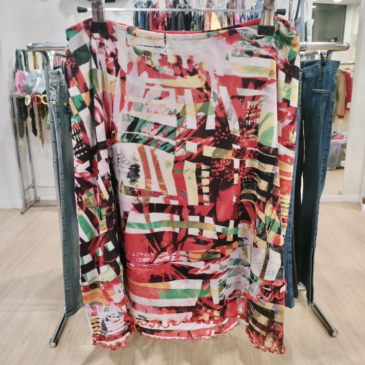 Colorful abstract long sleeve blouse with red, green, and yellow patterns in a boutique.