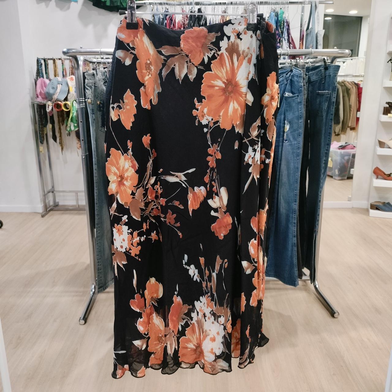 Black floral skirt with orange and white flowers hanging in a fashion boutique