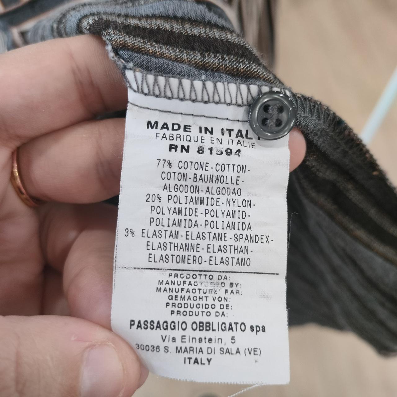 Clothing label held by a hand with text and product details