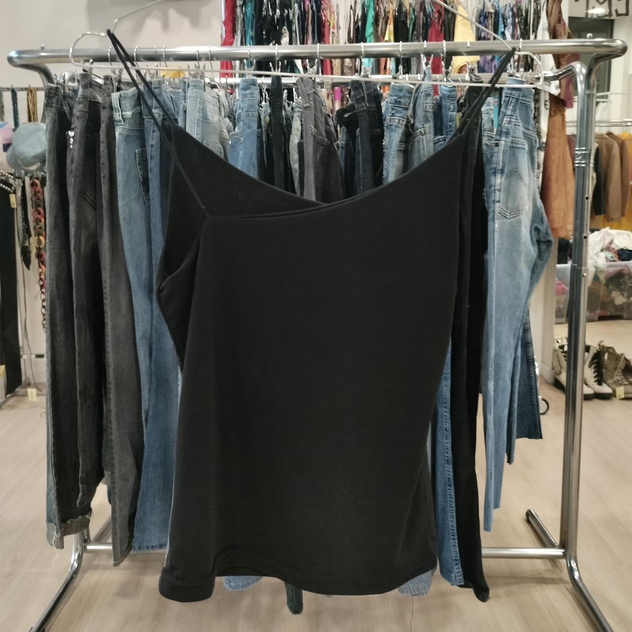 Black top hanging on a rack with jeans in a store setting