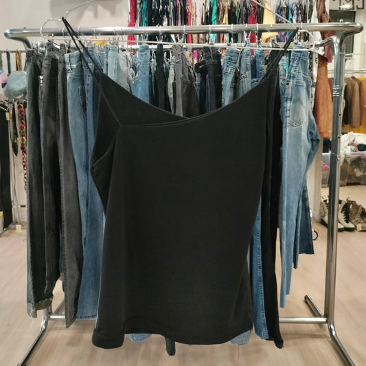 Black top hanging on a rack with jeans in a store setting