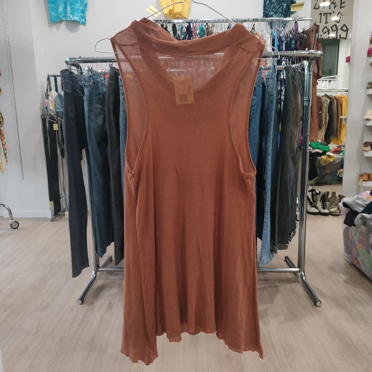 Sleeveless rust-brown flowy tank top hanging in a second hand clothing store