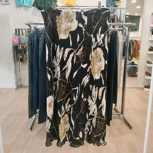 Black floral midi skirt with beige and white flowers, displayed in a second hand fashion store