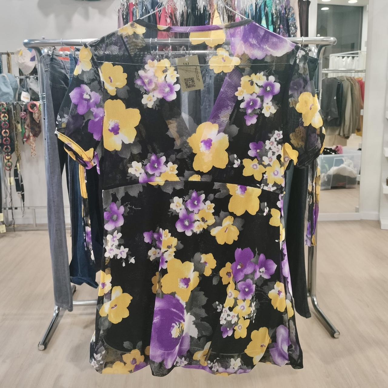 Black mesh short-sleeve top with yellow and purple floral print on store rack
