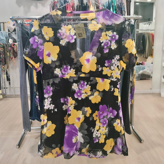 Black mesh short-sleeve top with yellow and purple floral print on store rack