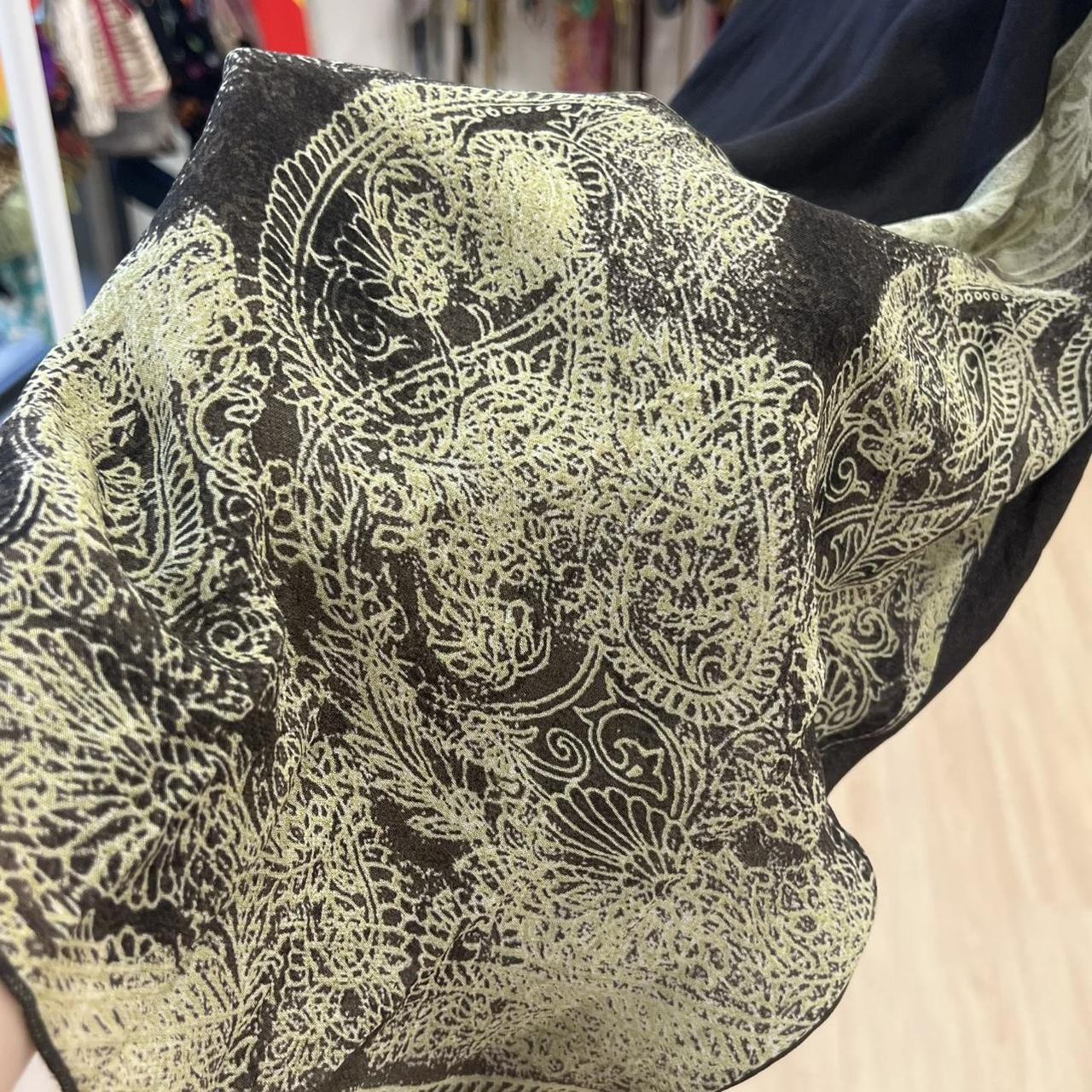 Close-up of black sheer fabric with intricate gold paisley and floral pattern, sustainable fashion