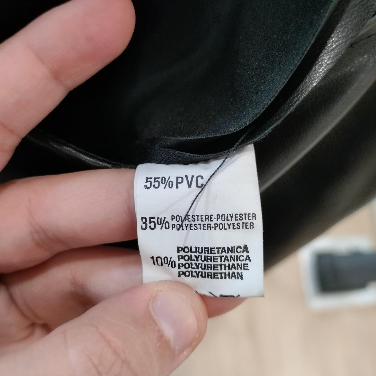 Hand holding a label with material composition details on a black product