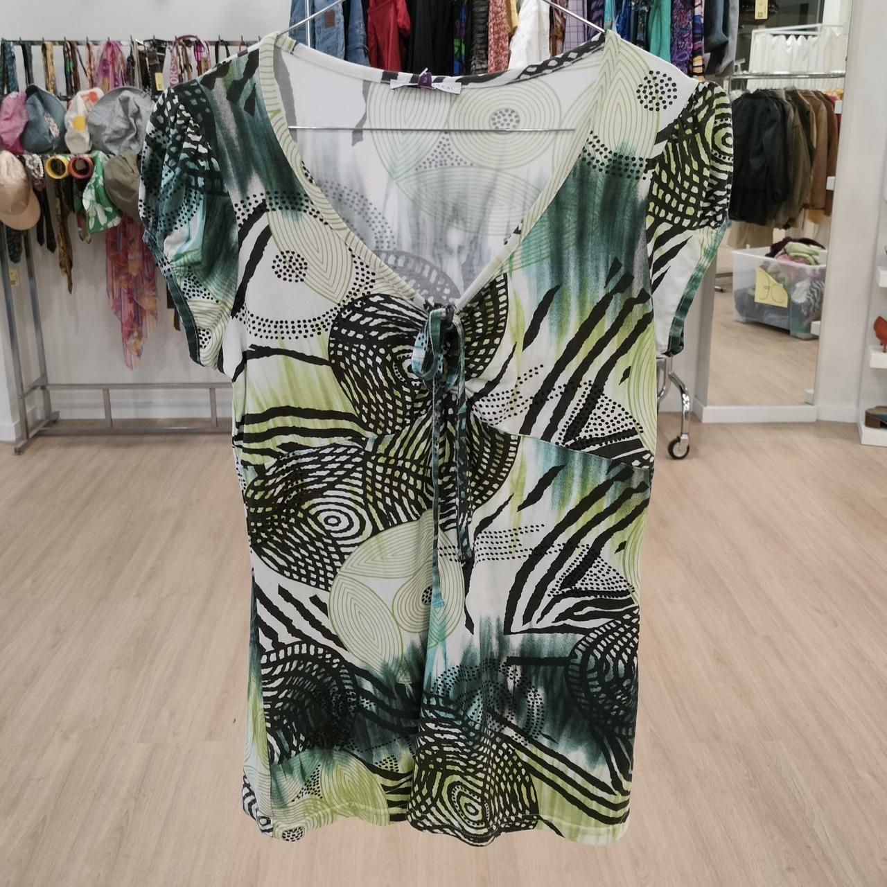Green and black abstract patterned short sleeve top with drawstring front in boutique setting