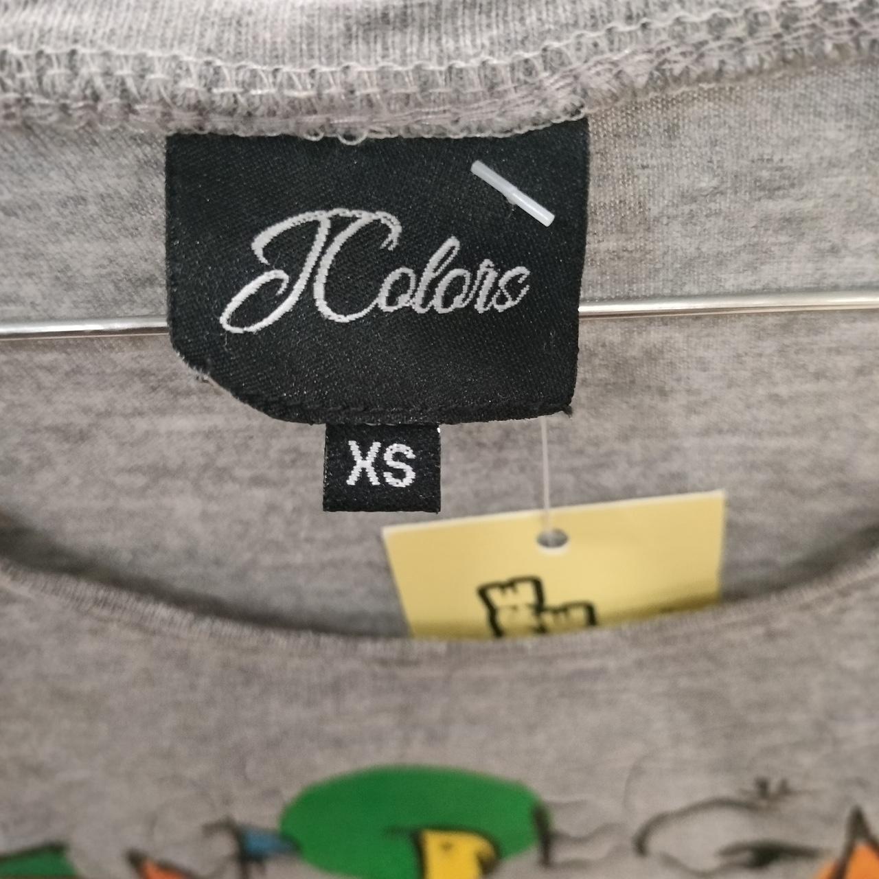 Grey crewneck t-shirt with JColors brand label and size XS tag, hanging on rack