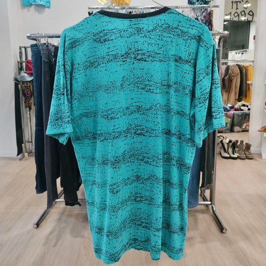 Teal patterned dress hanging on a rack in a store setting