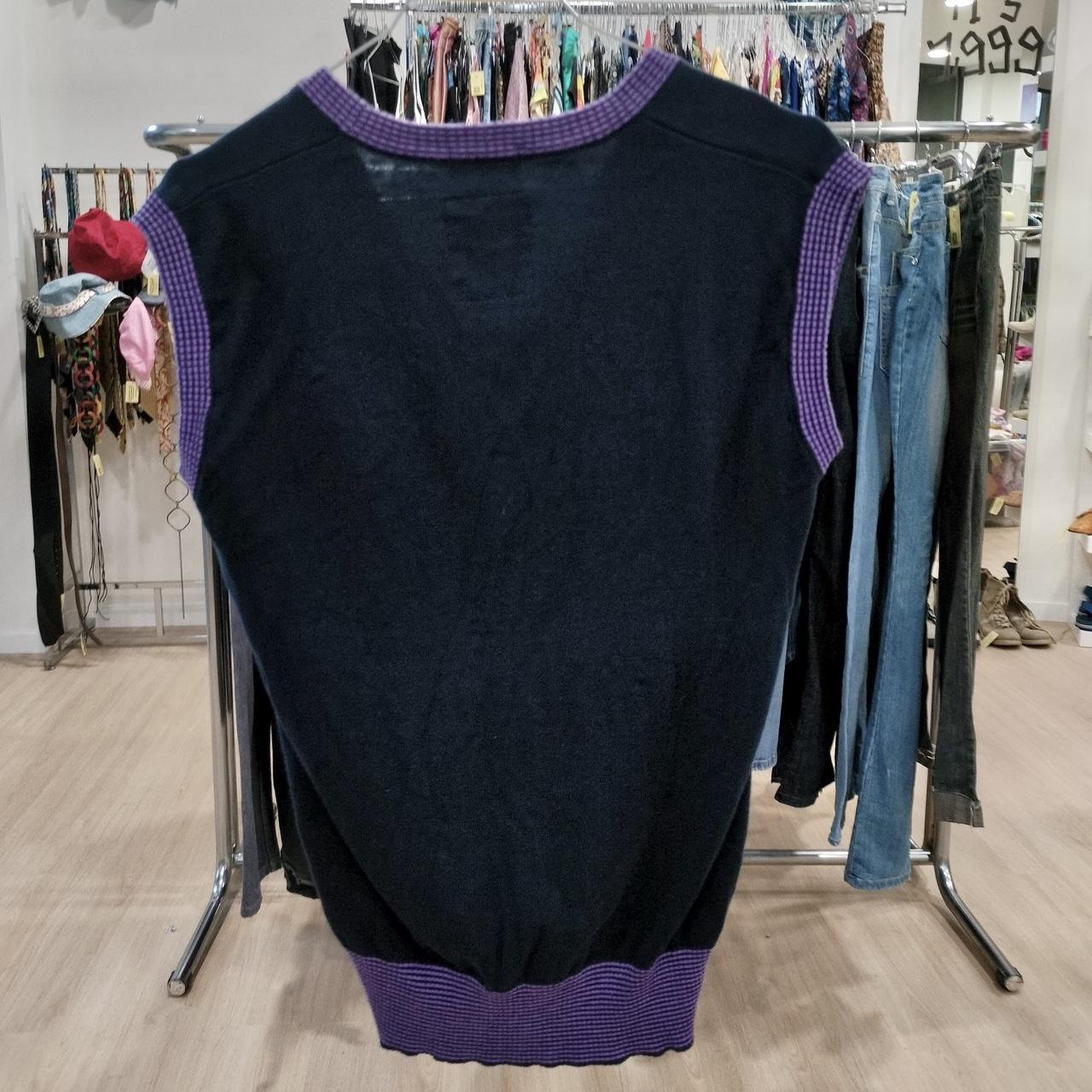 Black sleeveless sweater with purple trim displayed in a second hand clothing store