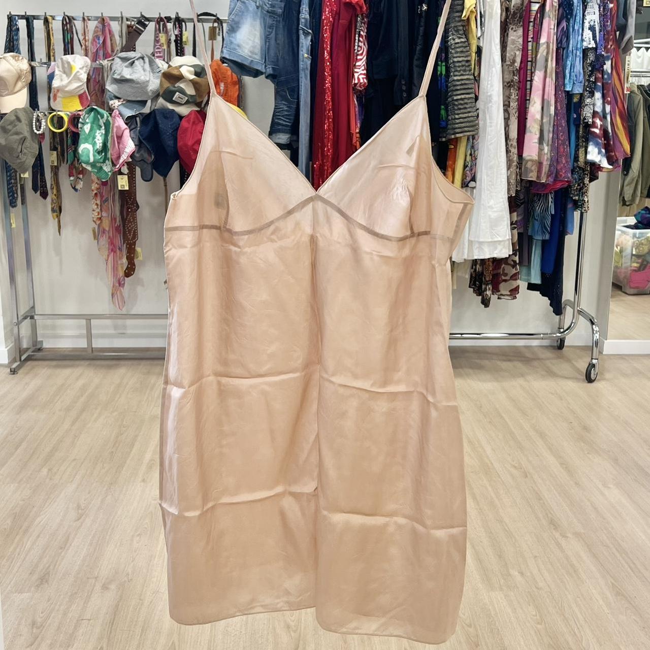 Beige dress hanging in a clothing store with racks of clothes in the background