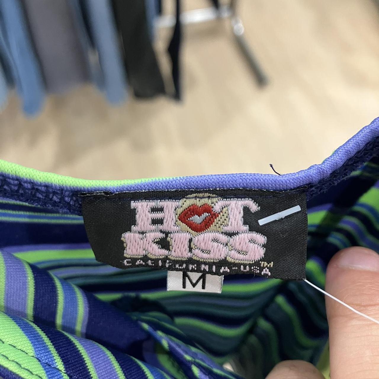 Close-up of a striped garment with a 'Hot Kiss' label on a blurred background