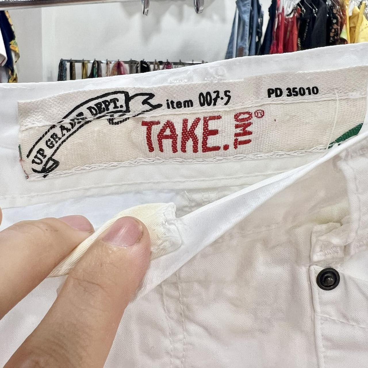 Close-up of white pants with vintage TAKE.TWO label, shown in a second hand clothing store.