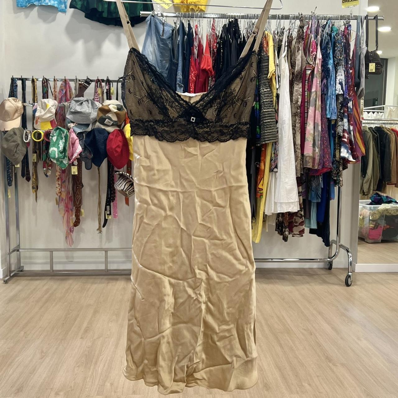 Beige slip dress with black lace top on hanger in second hand fashion store