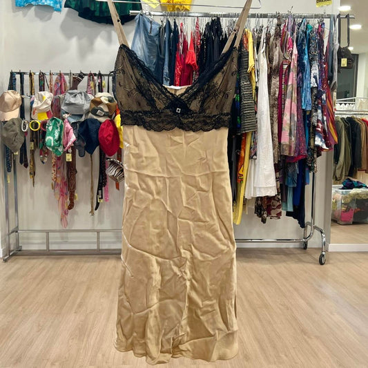 Beige slip dress with black lace top on hanger in second hand fashion store