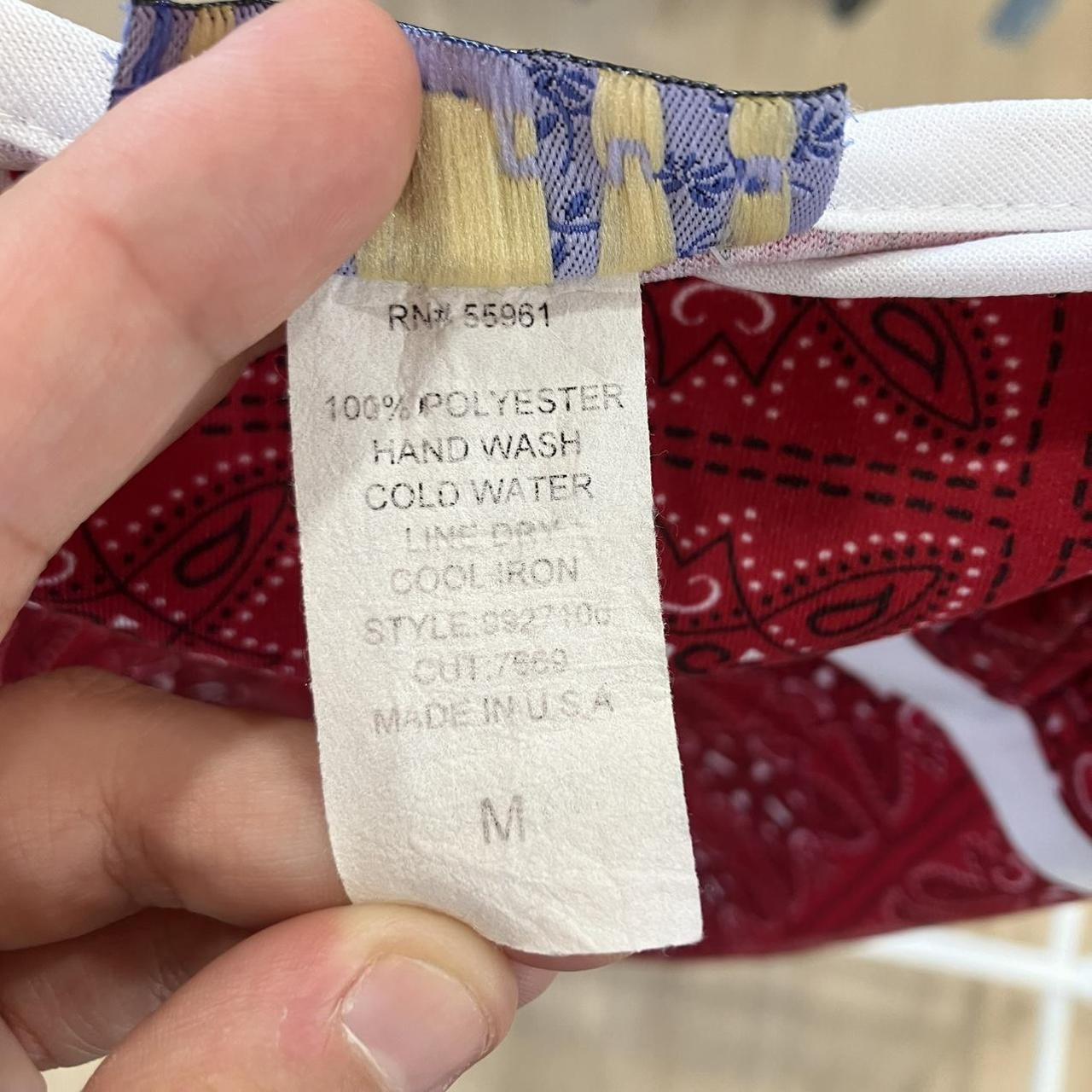 Close-up of a clothing tag with washing instructions and material details, held by a hand