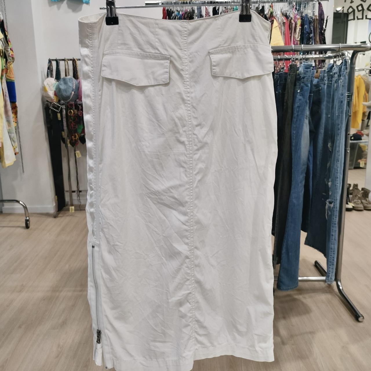White midi skirt with flap pockets and side zipper, displayed in second hand clothing store