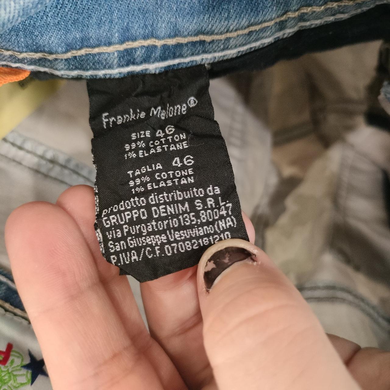 Close-up of denim jeans care label showing size, fabric content, and distributor details.