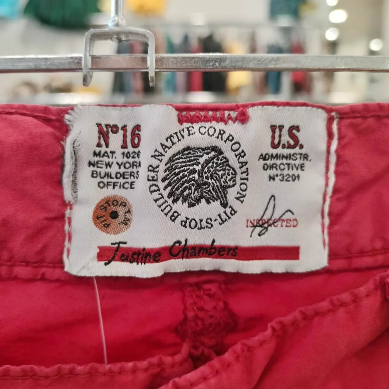 Close-up of a red garment label with stitched text and Native American head graphic