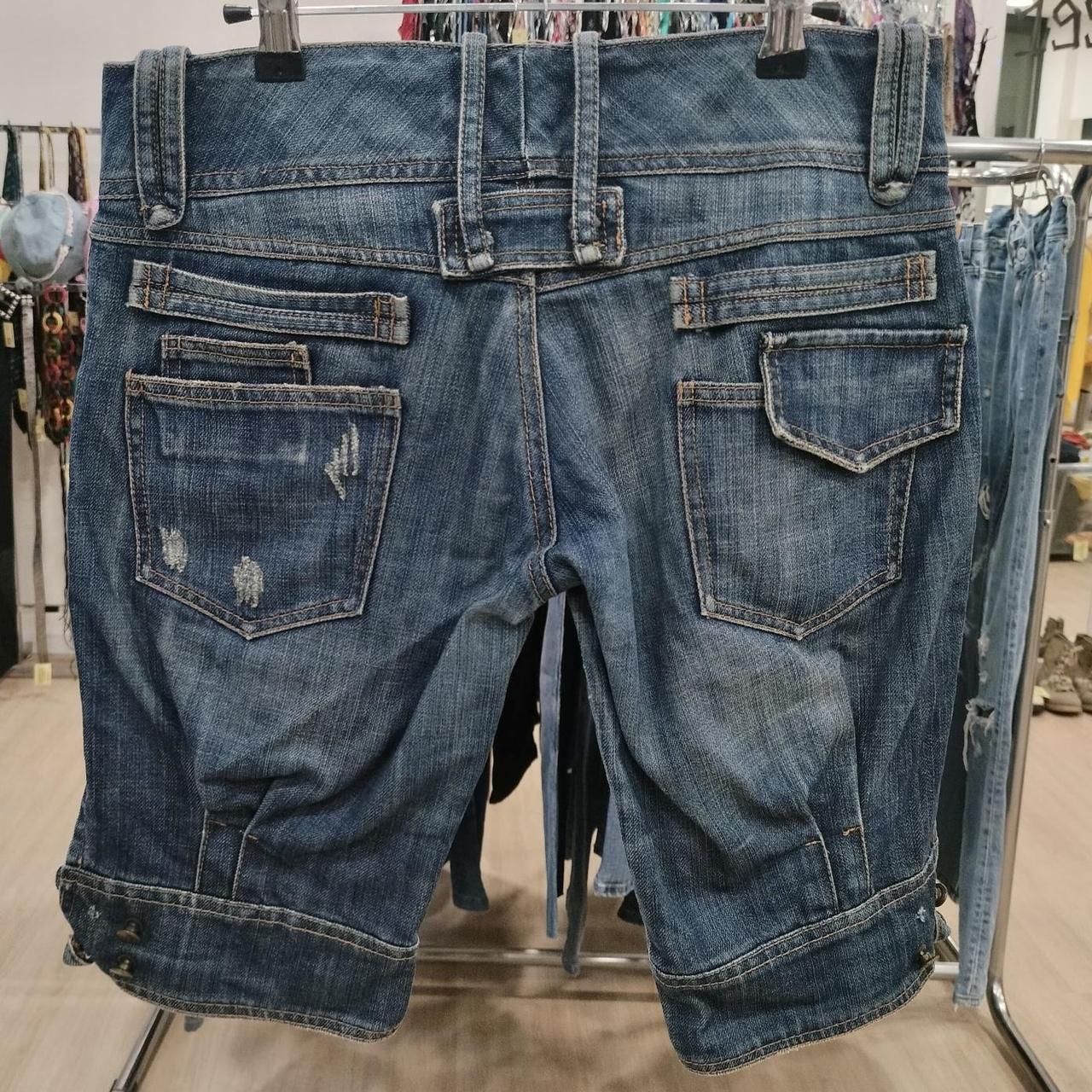 Distressed denim shorts with rolled cuffs and multiple back pockets on store display rack
