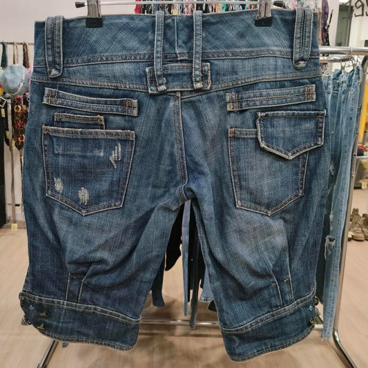 Distressed denim shorts with rolled cuffs and multiple back pockets on store display rack