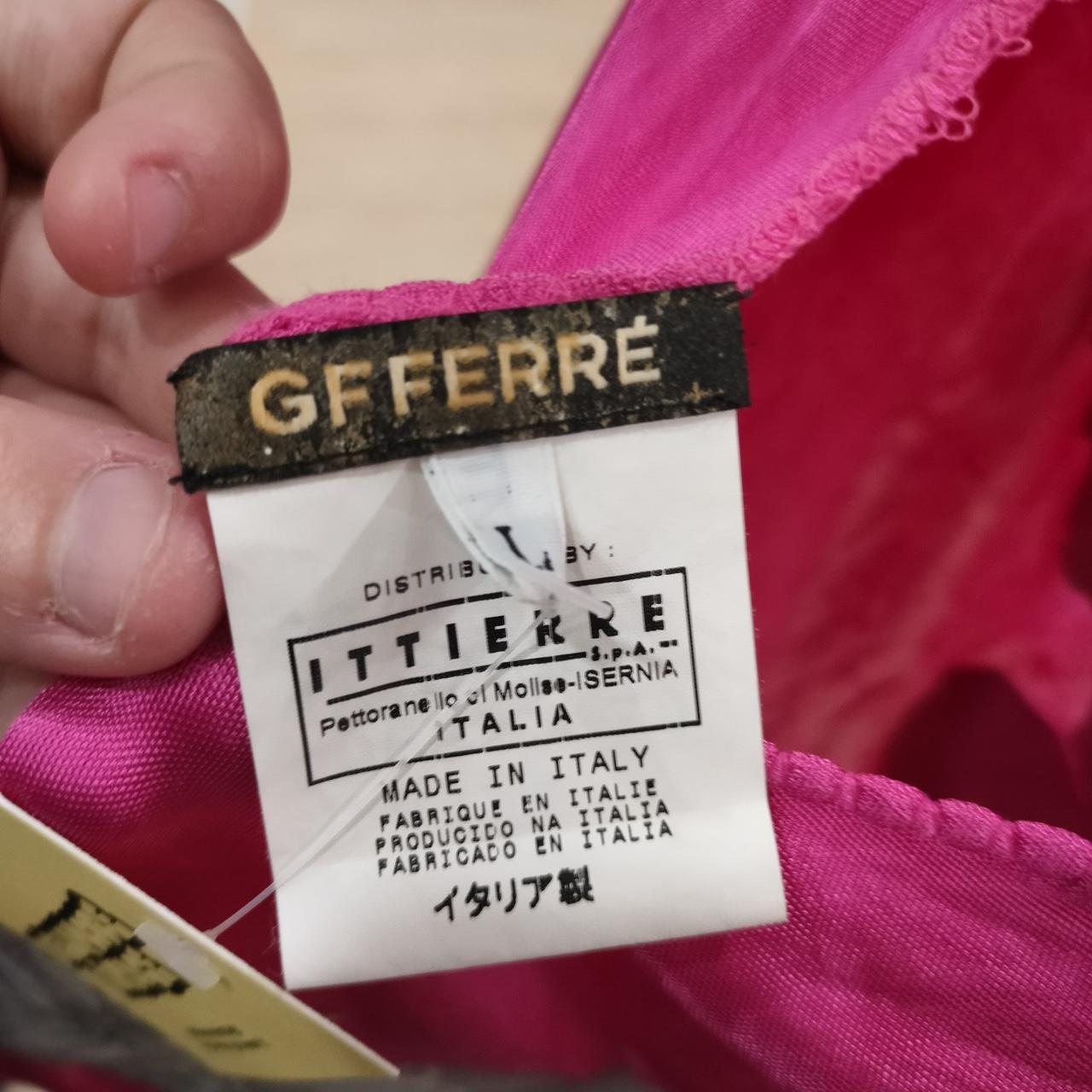 Close-up of a clothing label with 'GFFERRE' and 'ITTIERI' branding on a pink fabric background