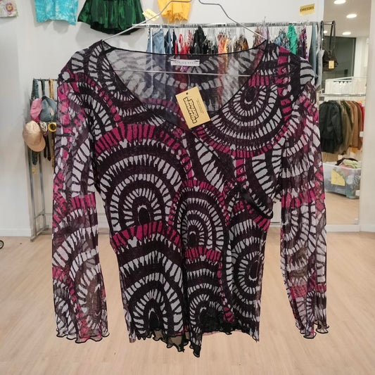 Sheer long sleeve top with black and magenta geometric pattern, hanging in thrift store