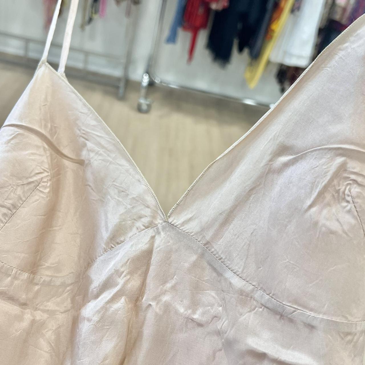 Close-up of a beige satin dress with a blurred background of a clothing store