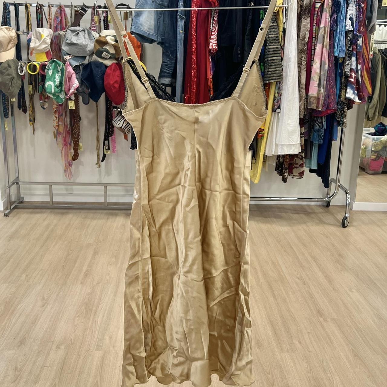 Beige satin slip dress with adjustable straps, displayed in a second hand fashion store.