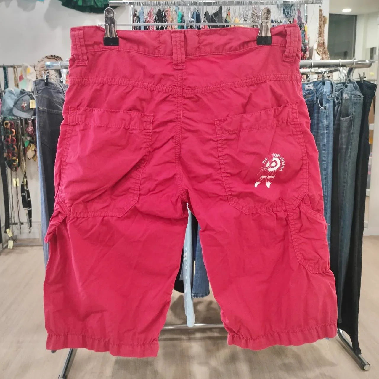 Red cargo shorts with back pockets displayed in a second hand fashion store