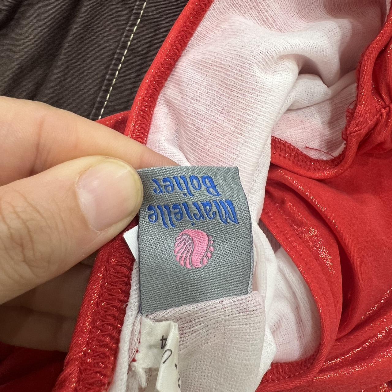 Close-up of a label on a red garment with visible text and a logo