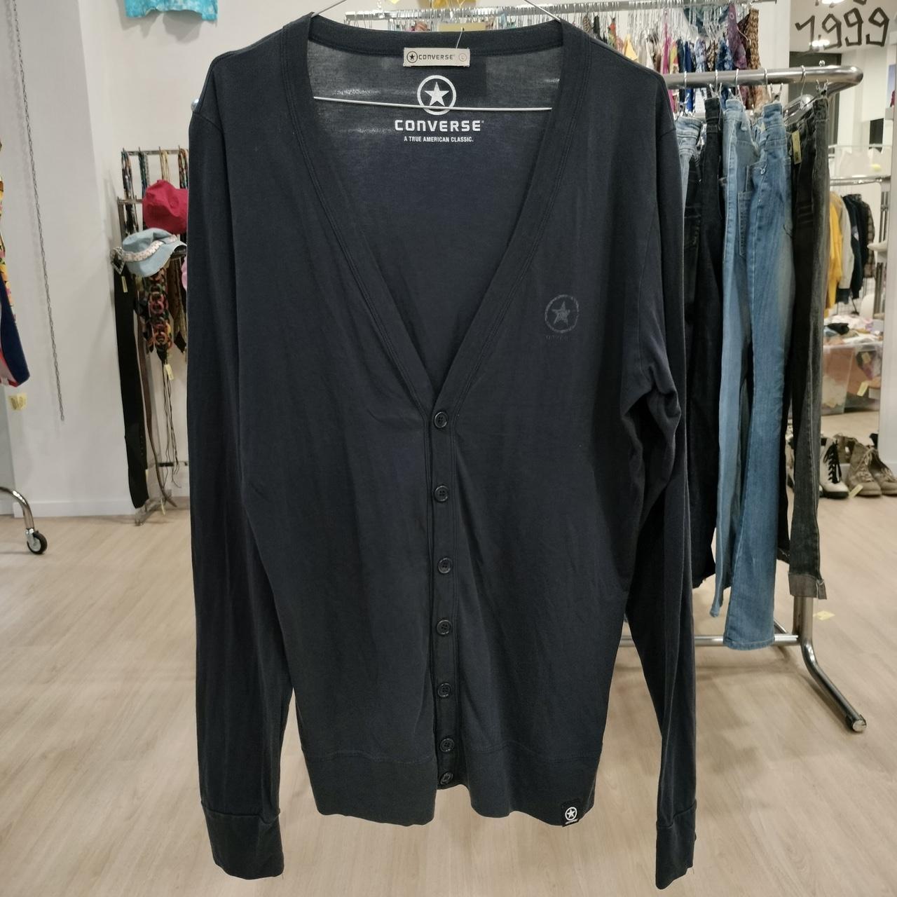 Black cardigan with Converse branding on a rack in a store setting