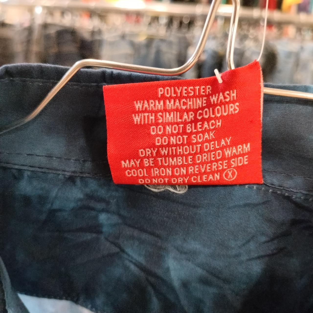 Red polyester clothing care label with washing instructions on blue garment