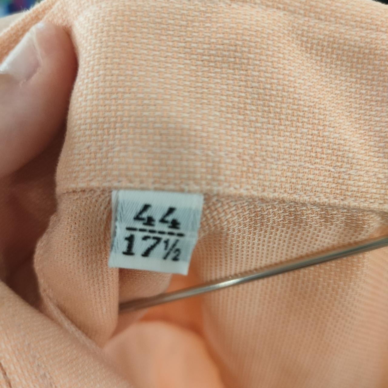 Close-up of a fabric with a size label on a peach-colored garment