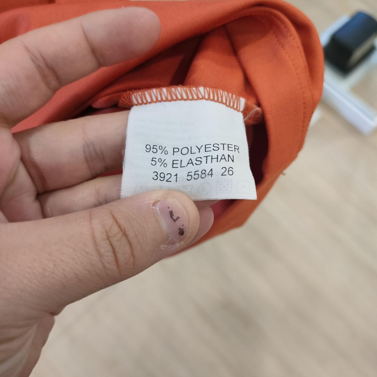 Hand holding a clothing label with fabric and blurred background