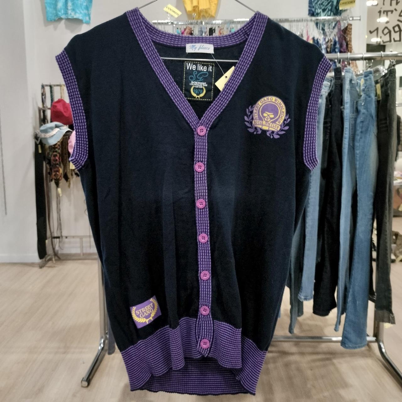 Vintage navy sleeveless cardigan with purple trim and buttons, streetwear patch, in a clothing store