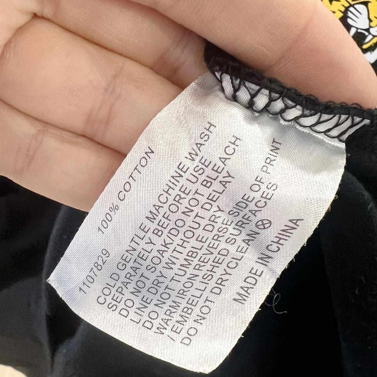 Clothing label with care instructions held by a hand