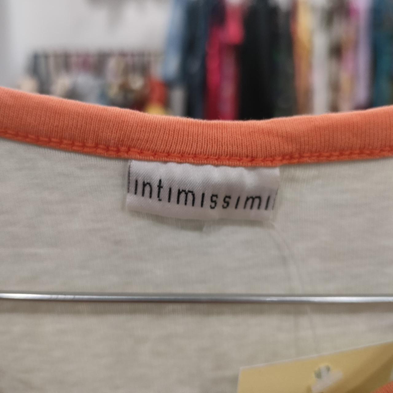 White top with orange neckline and clothing label, sustainable fashion detail