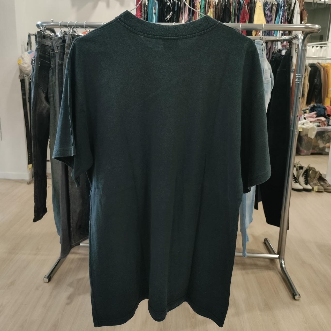 Dark green t-shirt on a rack with clothes in the background