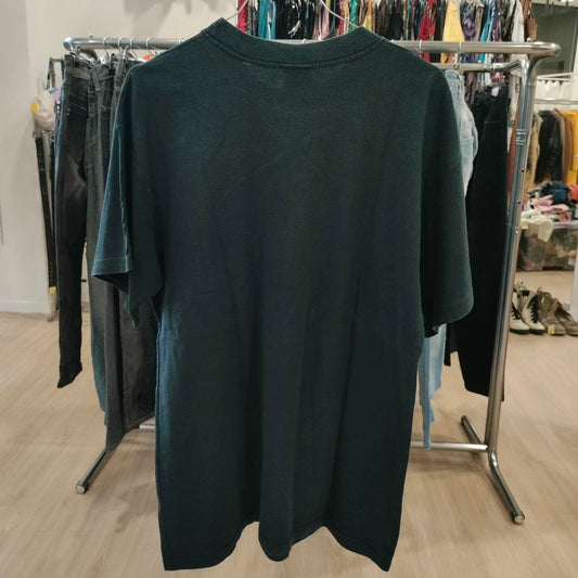 Dark green t-shirt on a rack with clothes in the background