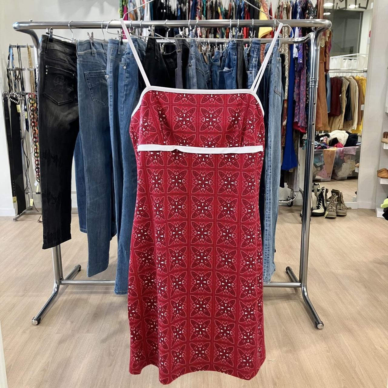 Red patterned dress on a rack with jeans and other clothing in a store setting