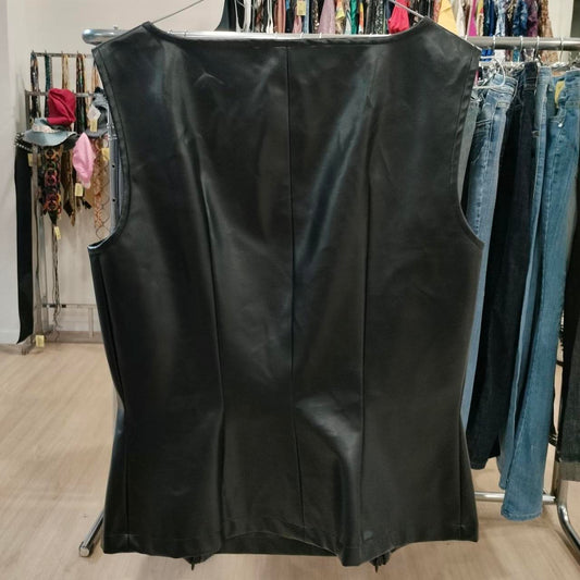 Black leather vest on a rack with other clothing items in the background