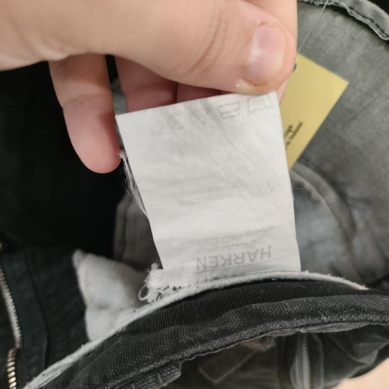 Close-up of a hand holding a clothing care label inside black denim jeans
