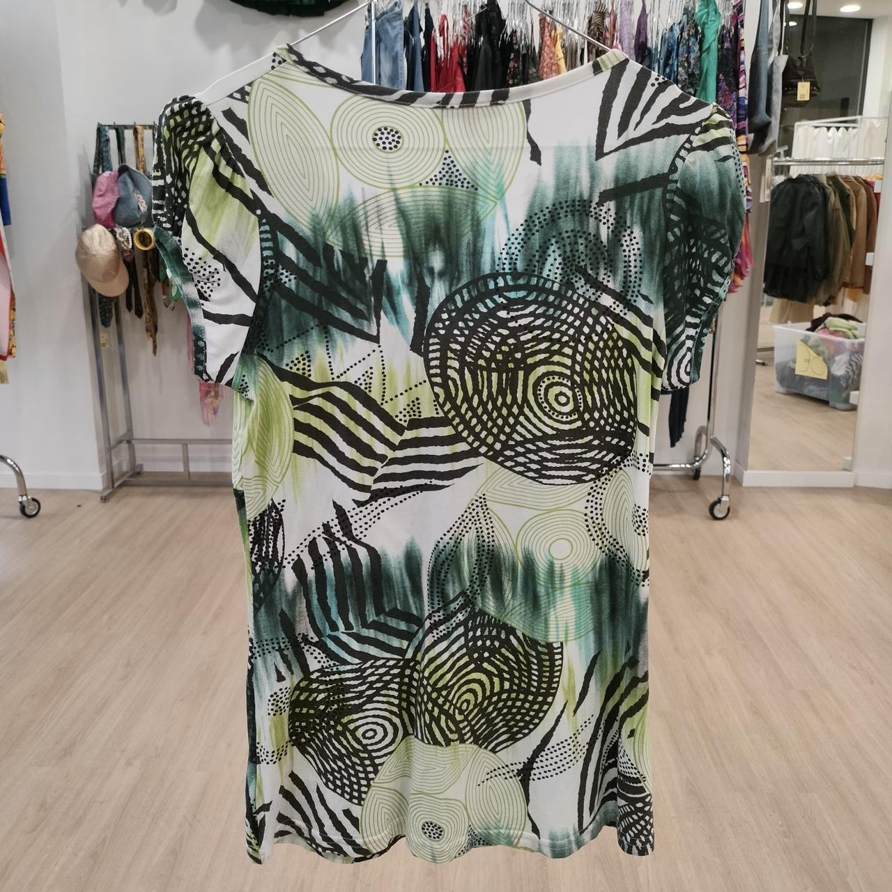Green and black abstract print women's top displayed in a boutique store setting