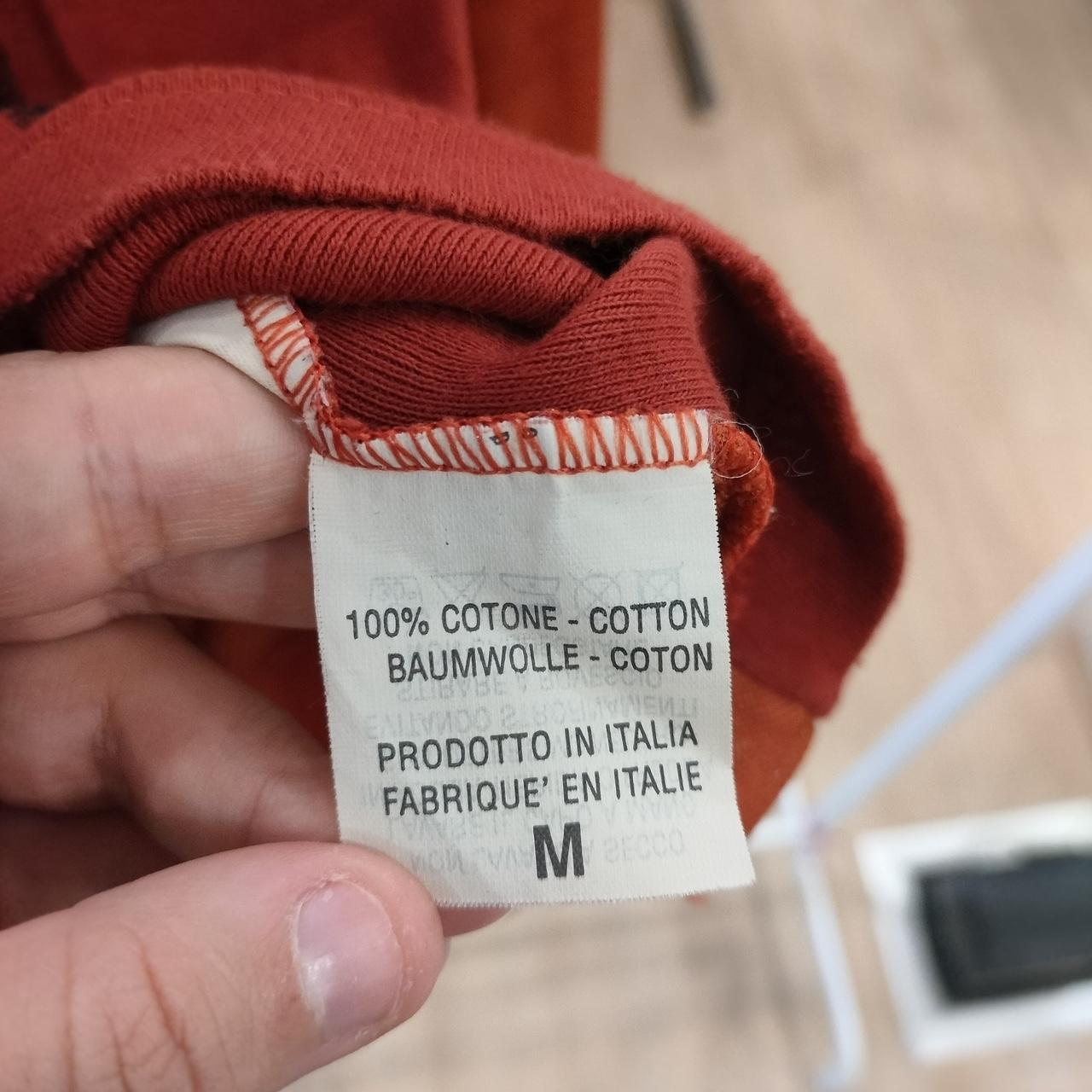 Close-up of a clothing label on a red garment with text indicating it's made in Italy