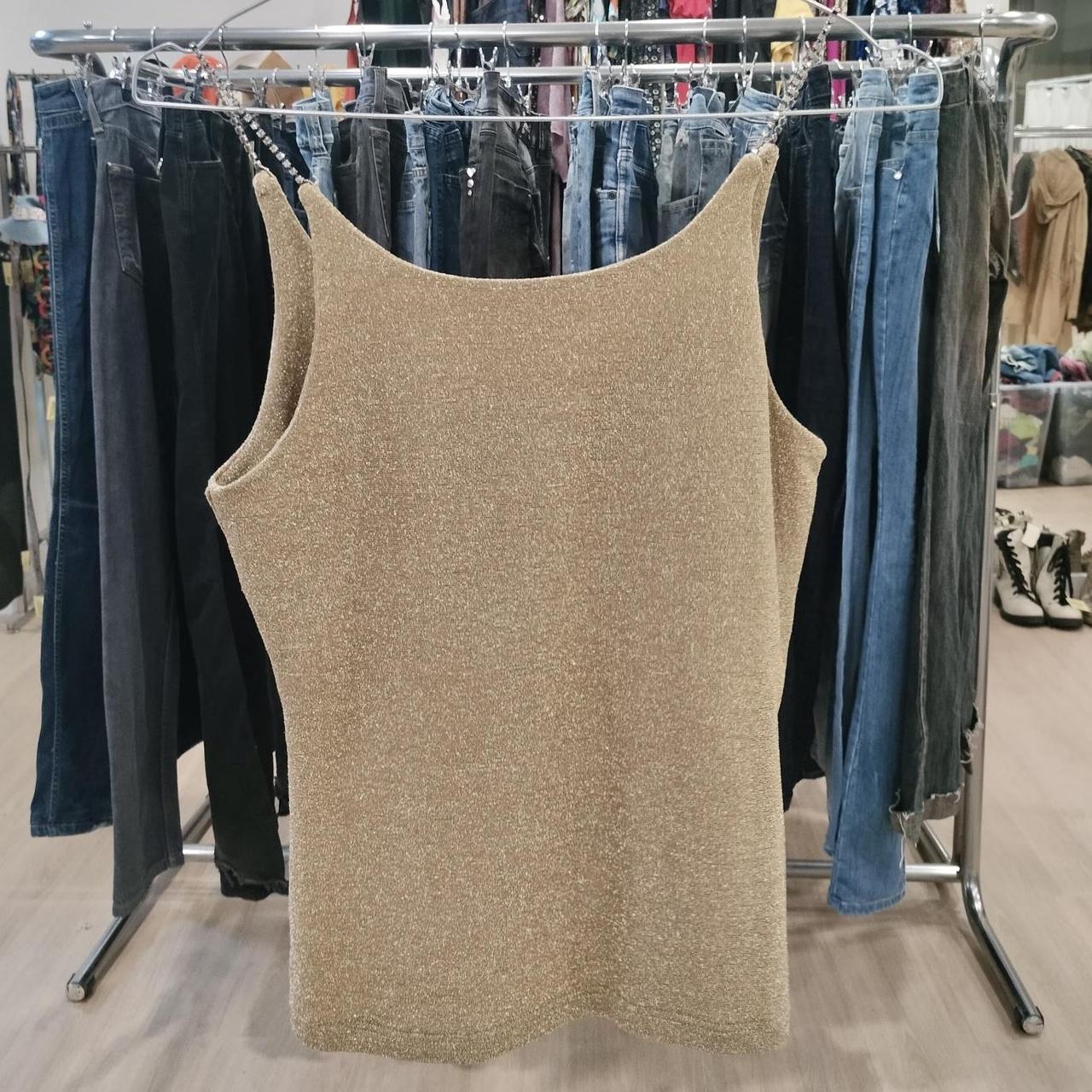Beige tank top on a rack with jeans in a store setting