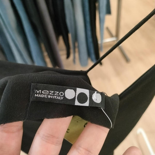 Close-up of a black garment with 'Mezzo Made in Italy' label held by a hand