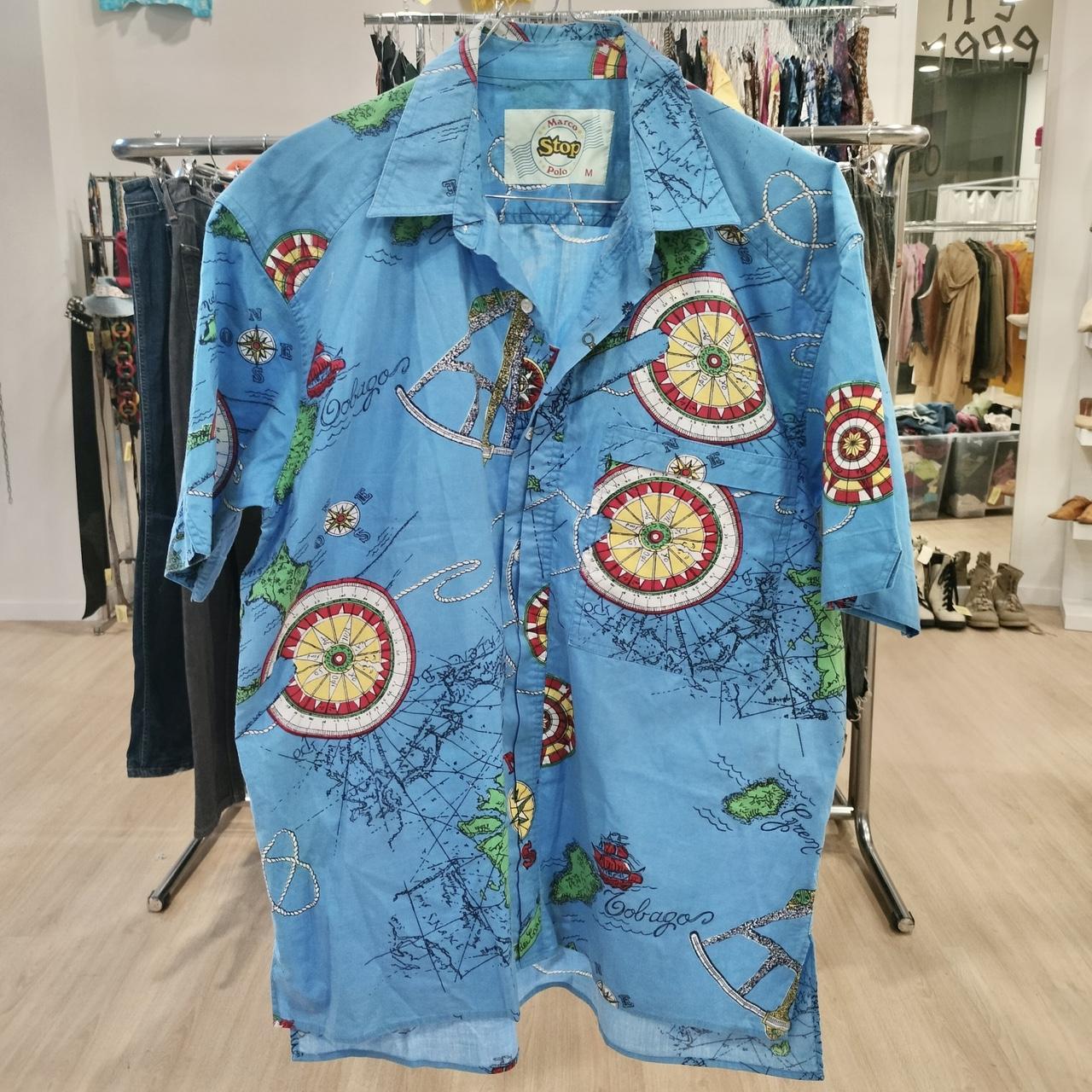 Blue vintage short-sleeve shirt with colorful nautical map print in a second hand clothing store